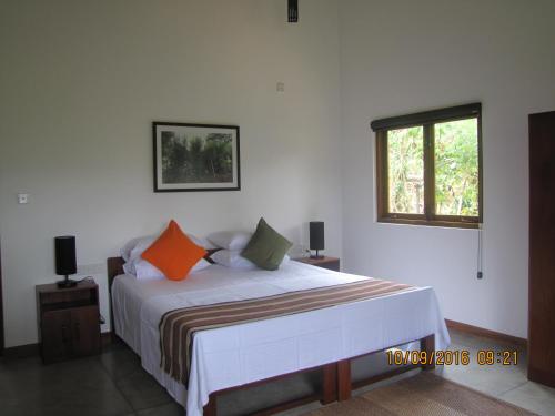 a bedroom with a bed with orange and green pillows at Zee's Garden in Matale