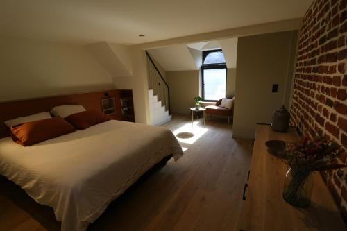 a bedroom with a bed and a brick wall at Chez Martine & Pierre in Baillonville
