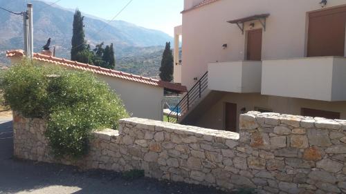 a house with a stone wall next to a building at Petrochori ApartHotel in Petrochori