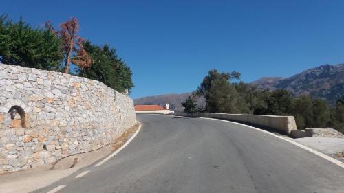 an empty road next to a stone wall at Petrochori ApartHotel in Petrochori