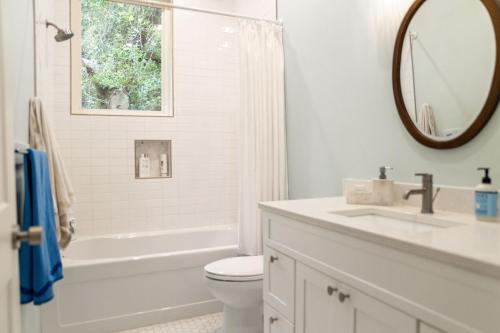 a white bathroom with a tub and a toilet and a sink at Blue Crest Architectural Treehouse Retreat in Ocean Springs