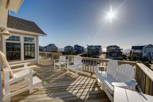 a wooden deck with white chairs and the beach at 7678 - Drumstick in Avon