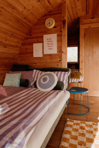 a bed in a log cabin with a clock on the wall at The Sleepy Crofter Glamping - Achiltibuie in Achiltibuie