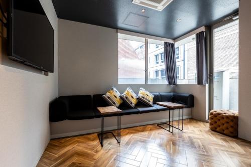 a living room with a black couch and windows at Sekine Building 4th floor - Vacation STAY 75338v in Tokyo