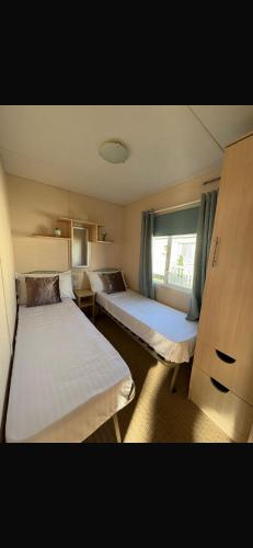 a small room with two beds and a window at J&A Caravan in Rhyl