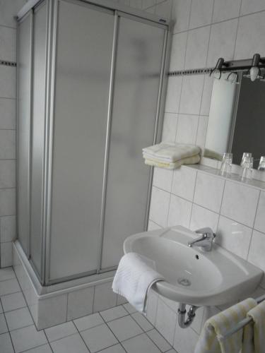 Westfälischer Hof في Lügde: حمام أبيض مع دش ومغسلة