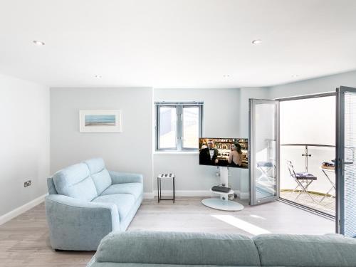 a living room with a blue couch and a tv at Apartment 19 in Newquay