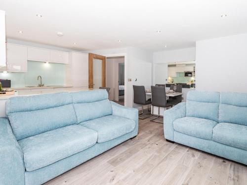 a living room with two blue couches and a kitchen at Apartment 19 in Newquay
