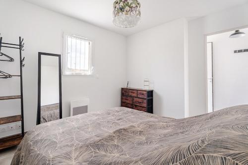 a white bedroom with a large bed and a chandelier at la pause detente, villa climatisée avec jardin et parking privés, à 5 mn de la mer, au calme in Martigues