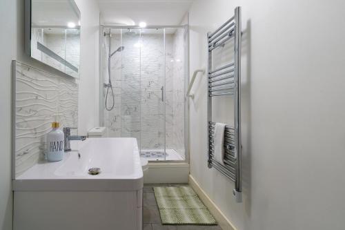 a white bathroom with a sink and a shower at Vantage Stays in Gloucester