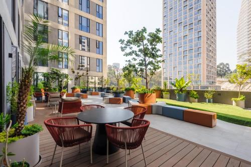 a rooftop patio with tables and chairs and buildings at Amazing Apartments in the Heart of Interlomas in Mexico City