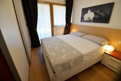 a bedroom with a bed and a night stand with a lamp at Eleonora 4A in Temù