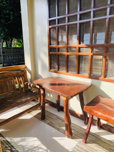 a wooden bench and a table and a window at Ayette's Bamboo Cottages in San Vicente