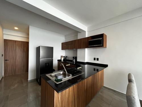 a kitchen with a black counter top and a refrigerator at Frente a la Playa con acceso directo AC Alberca y Elevador in Veracruz
