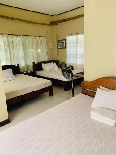 a room with two beds and a fan in it at Ayette's Bamboo Cottages in San Vicente