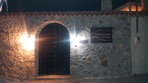 a stone wall with a door and a sign on it at Petrochori ApartHotel in Petrochori