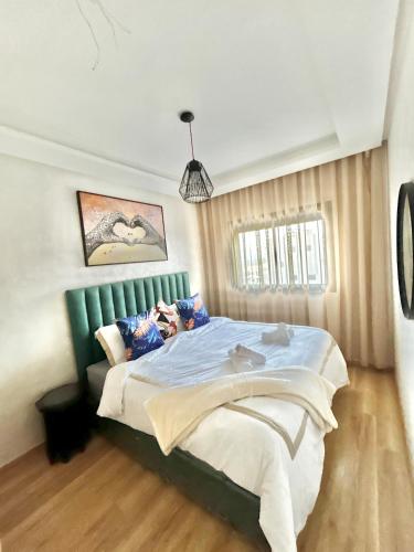 a bedroom with a large bed with a green headboard at Chic studio with sea view, Wi-Fi & pool in Aïn Harrouda