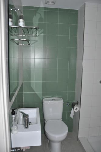 a green tiled bathroom with a toilet and a sink at Can Déu del Firal in Cassà de la Selva