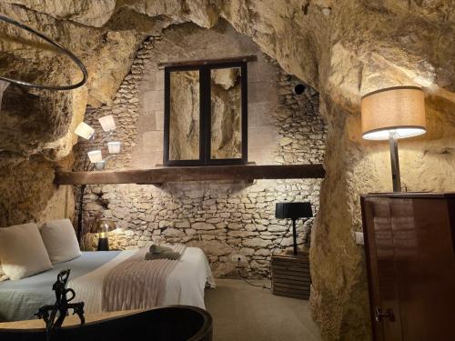 a bedroom in a cave with a bed and a window at La Grotte du Moulin in Noyers-sur-Cher