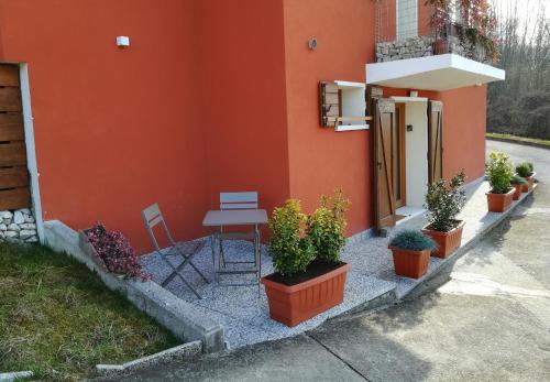 a house with a table and potted plants on the side at La Libellula Rossa in Puos dʼAlpago