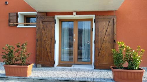 a wooden door on a building with two potted plants at La Libellula Rossa in Puos dʼAlpago