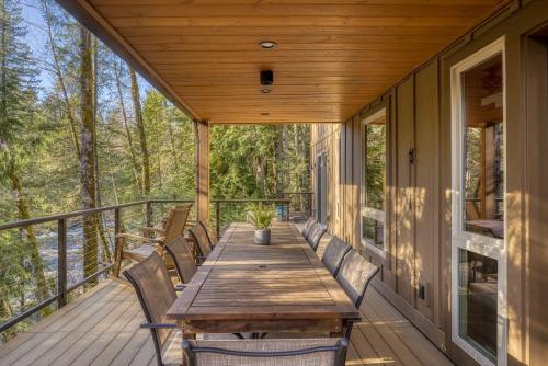 a wooden table on a deck with benches at Roaring River Lodge Riverfront Fire pit EV Plug in Rhododendron