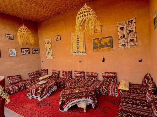 a living room with couches and a red rug at Dar Talmoudi ,Traditional Riad, Local Food, Camel , Desert Excursions in Tagounite