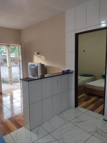 a room with a counter with a tv and a bedroom at Pousada do Ribeirão in Andrelândia