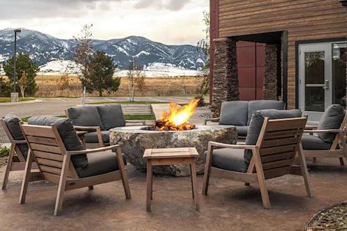 a fire pit with four chairs and a table and a fire place at Residence Inn Bozeman in Bozeman
