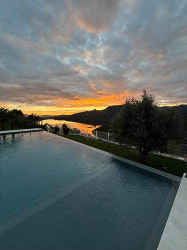 a large swimming pool with a sunset in the background at Estrela do Gerês - Casa Fernandes in Outeiro