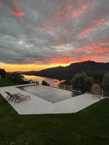 a swimming pool with a sunset in the background at Estrela do Gerês - Casa Fernandes in Outeiro