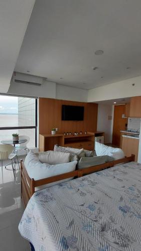two beds in a large room with a television at Tropical Executive Hotel Flat 205 in Manaus