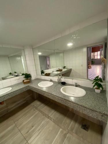 a bathroom with three sinks and two mirrors at Hostel Las Lengas in Buenos Aires