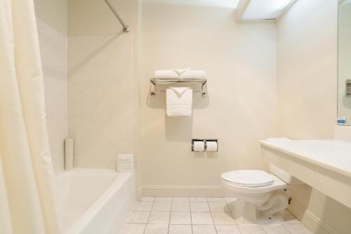 a white bathroom with a toilet and a sink at The Monarch Resort in Pacific Grove