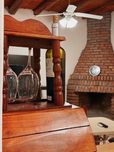 a bottle of wine and glasses on a wooden shelf at En Armonía in Tinogasta