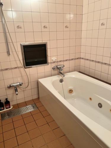 a bathroom with a tub and a tv on the wall at ホテル アイアンプレミアム 西宮北店 男塾ホテルグループ in Nishinomiya