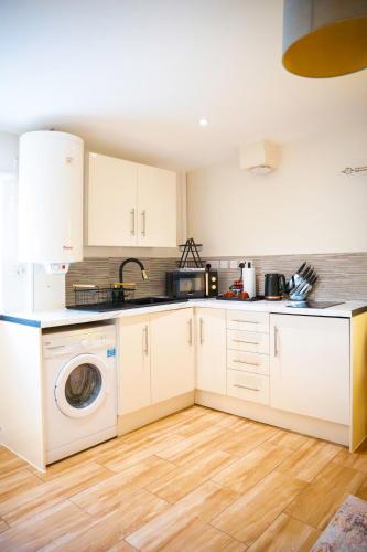 a kitchen with white cabinets and a washing machine at City-Centre Gem Modern Top-Floor Retreat in Cambridge