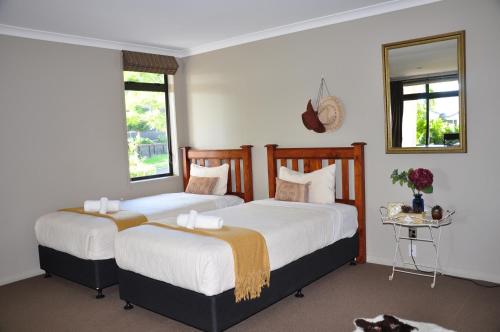 two beds in a room with two windows at Parnwell Villa Apartment - The Tropical Oasis in Tauranga