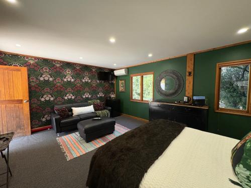 a bedroom with green walls and a bed and a couch at El Grouso in Blenheim