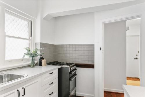 a white kitchen with a stove and a sink at Langley Park 2BR CBD Character Apt with FREE Parking in Perth