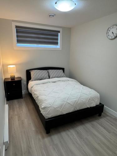 a bedroom with a bed and a clock on the wall at Alake Villa in Saskatoon