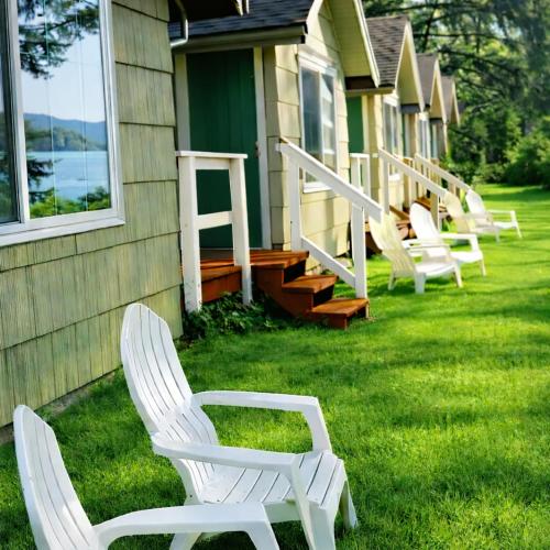 a row of white chairs sitting on a lawn next to a house at Siltcoos Station in Siltcoos