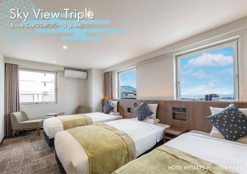 a hotel room with three beds and a window at HOTEL MYSTAYS Hakodate Station in Hakodate