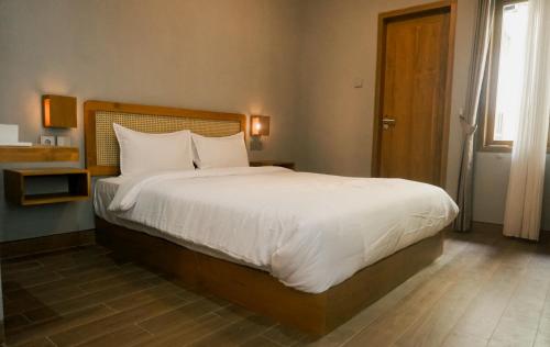 a bedroom with a large bed with white sheets and pillows at The Umbu Stay Banyuwangi in Banyuwangi