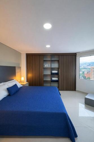 a large bedroom with a blue bed and a window at Hotel Ivanna - Laureles in Medellín