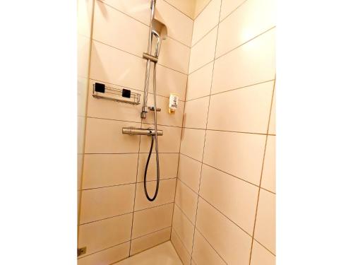 a shower in a bathroom with white tiles at Bernsteinsee Homes and Ferien Beach House 2 in Sassenburg