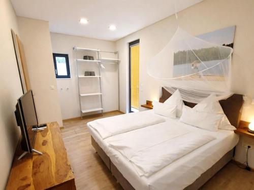 a bedroom with a large white bed and a window at Bernsteinsee Homes and Ferien Beach House 2 in Sassenburg