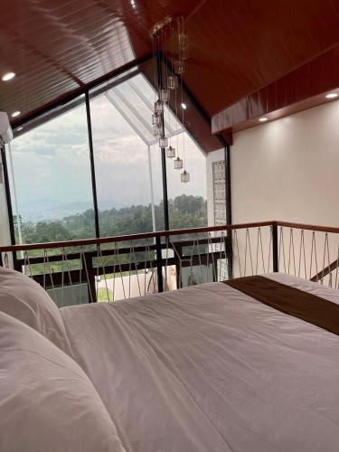 a bedroom with a bed and a large window at Villa with Jacuzzi, Damar Ningrum 4 in Tutugan