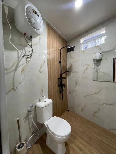 a bathroom with a white toilet and a shower at Villa with Jacuzzi, Damar Ningrum 4 in Tutugan