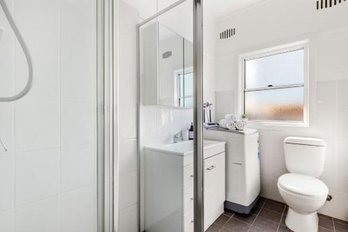 a white bathroom with a toilet and a sink at Beauts - Pet Friendly - 5 Mins Walk to Beach in Culburra Beach